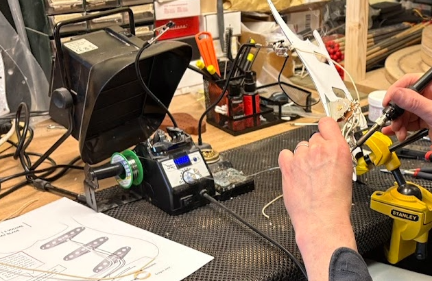 A student soldering a guitar circuit during the guitar electronics class